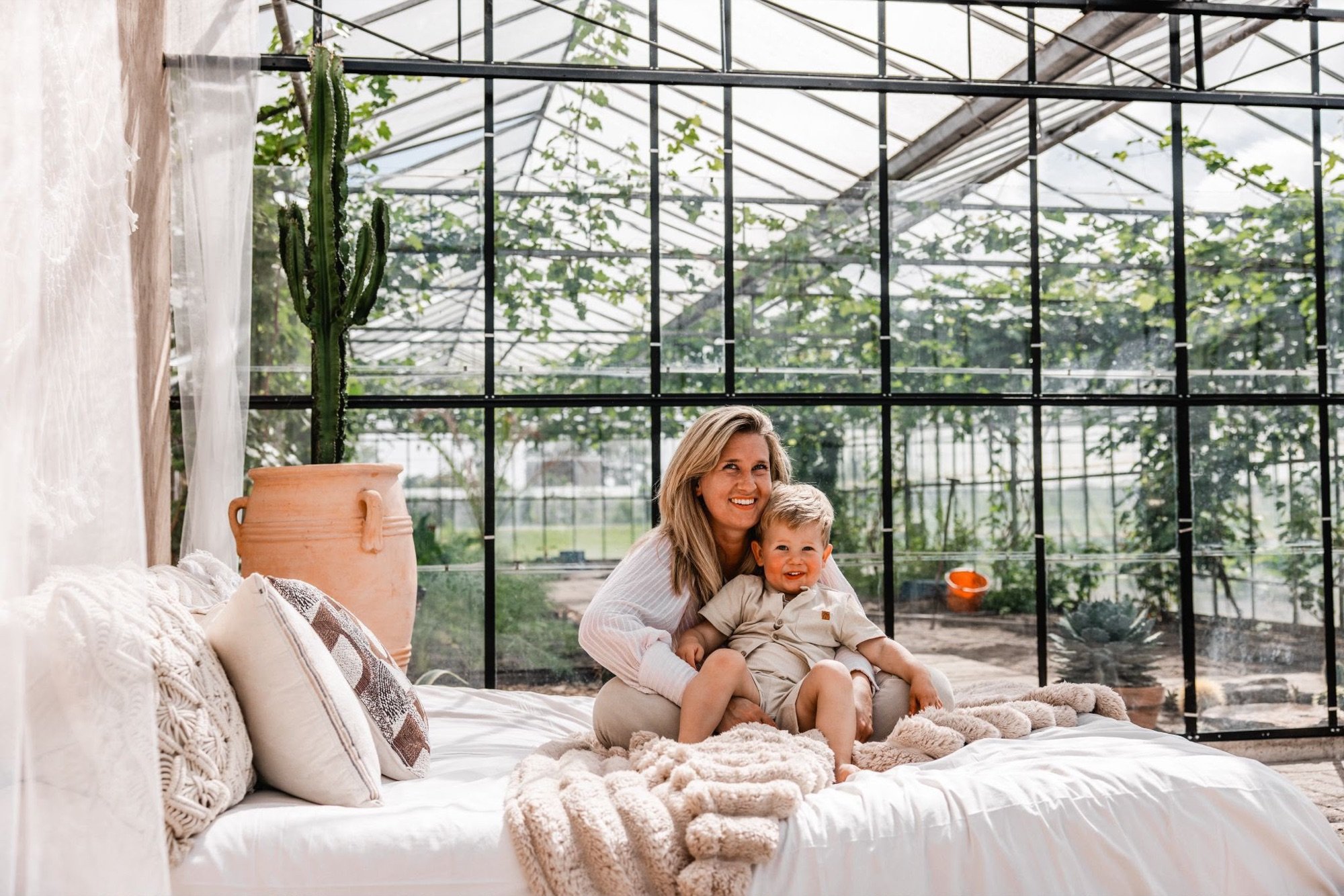 Moeder en kind samen op het bed met zicht op het glazen dak van de kas