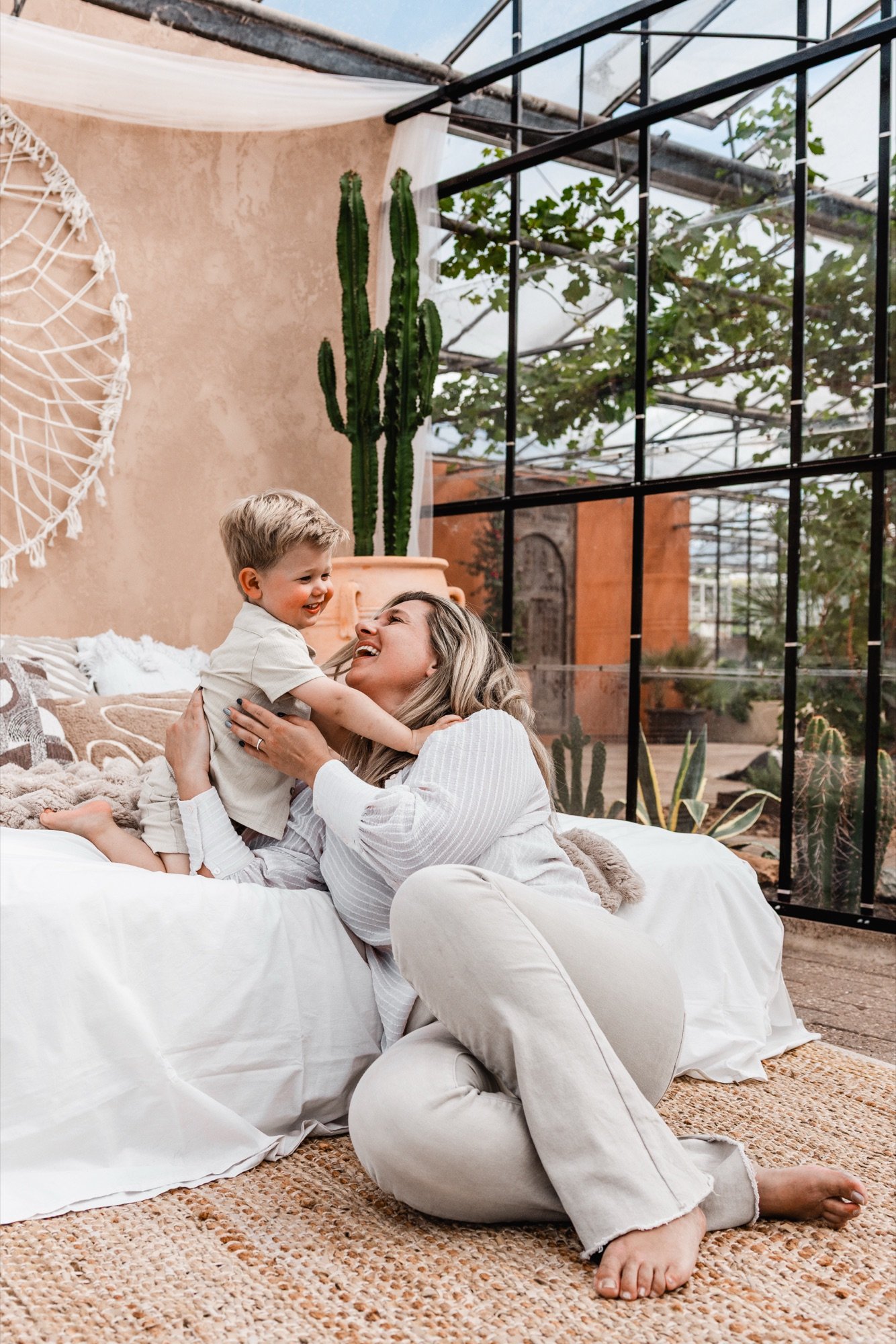 Moeder en kind lachen samen op het bed in de lichte kas
